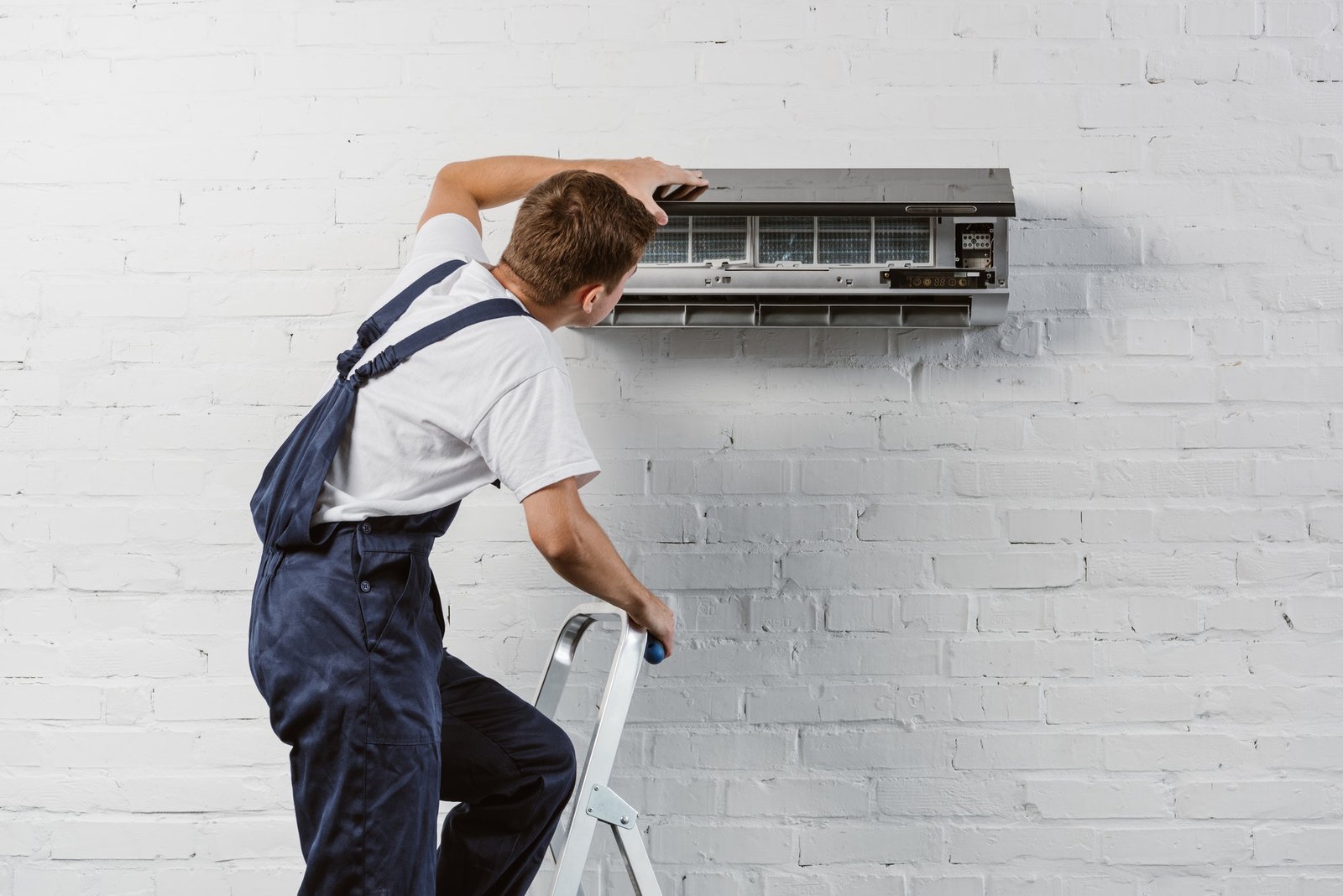 rear view of air conditioner repairman standing on stepladder
